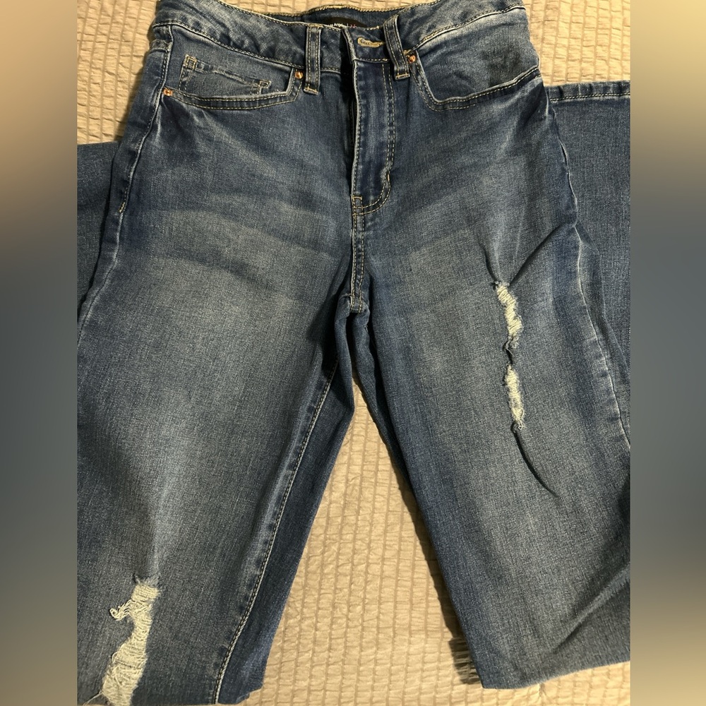 Distressed blue denim jeans with frayed hem